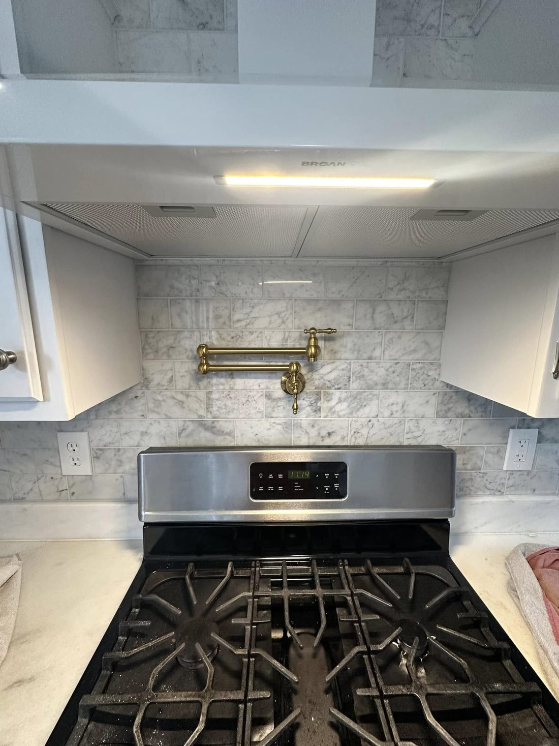 Marble tile backsplash with brass pot filler
